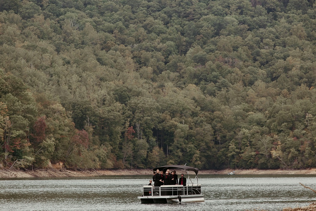Groomsmen on Nantahala Lake in a pontoon boat for a pre-ceremony adventure in early autumn with leaves just starting to turn